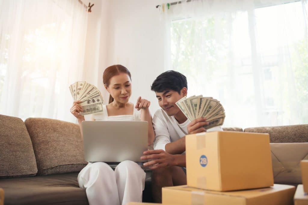 A happy couple holding fans of cash, celebrating the successful funding of their loan application.