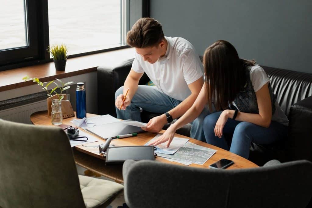 A couple using their recently acquired funds to plan an international trip while reviewing maps and travel costs.