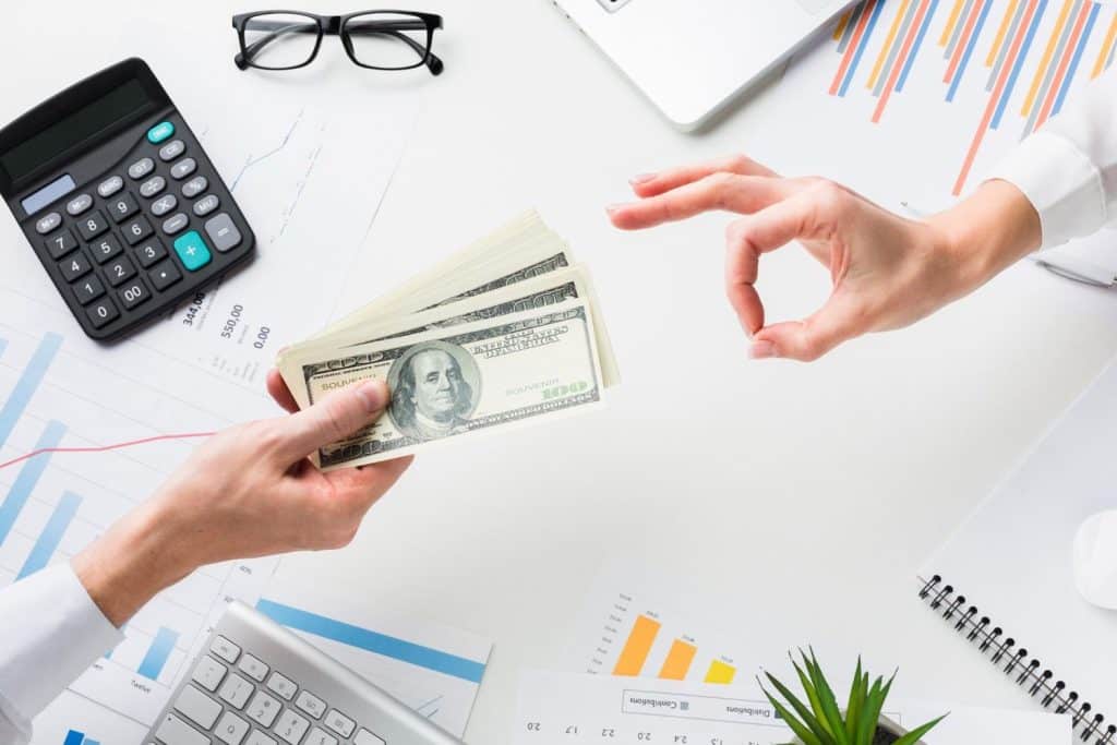 Overhead view of a lender handing over cash, representing the final approval and disbursement of an unsecured loan.