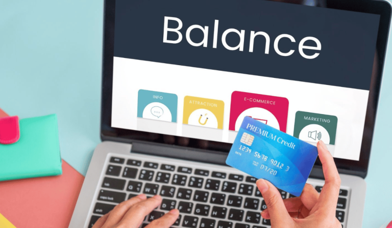 A person holds a "Premium Credit" card while viewing a laptop screen displaying "Balance," illustrating the first step in calculating a credit utilization ratio.
