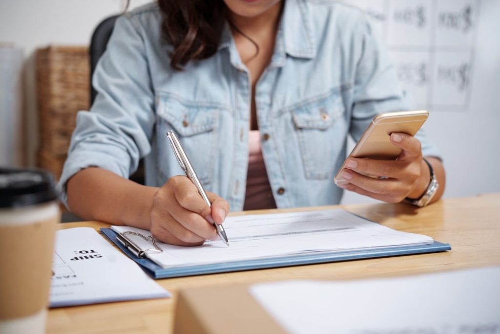 A woman signs documents while researching personal loan vs credit card options for managing debt.
