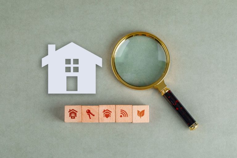 Magnifying glass over house icons representing a detailed search for how to find cheap homes and properties.