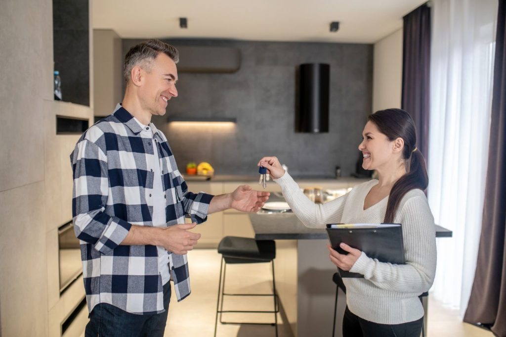 Realtor handing keys to a smiling client who secured one of the best first time home buyer loans.
