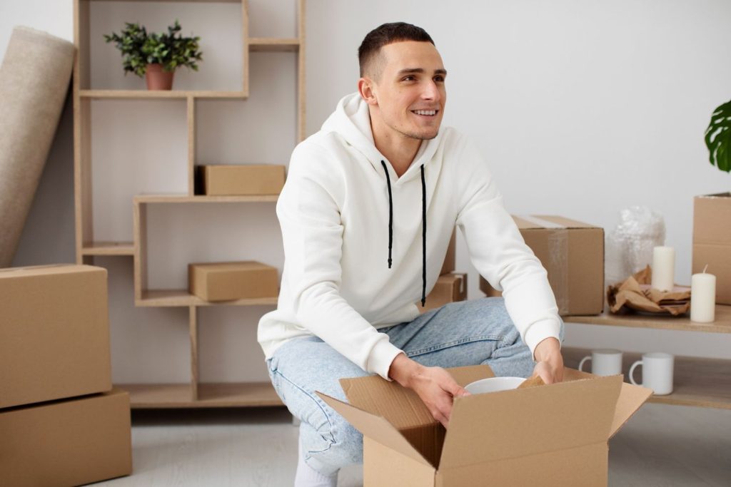 A happy man unpacking boxes in his new apartment purchased using first time home buyer loans.