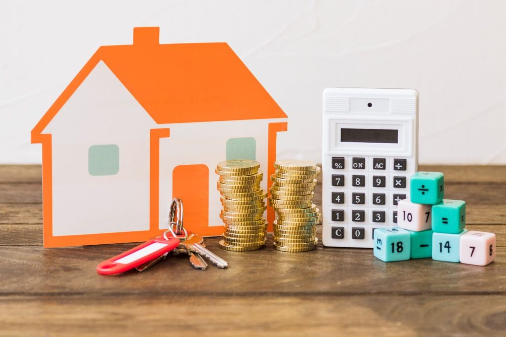 Calculator, keys, and coins next to a paper house representing home equity line of credit calculations.