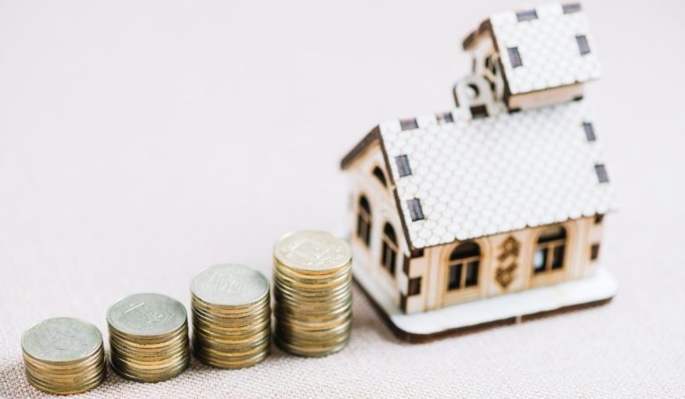 Stacks of coins increasing in height next to a model house showing home equity line of credit growth.