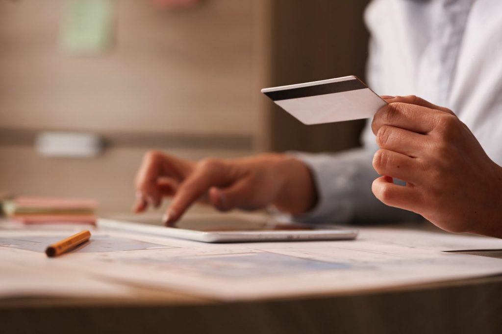 A woman uses a tablet while holding a credit card.