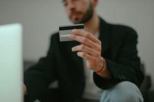 Man holding a credit card while using his laptop