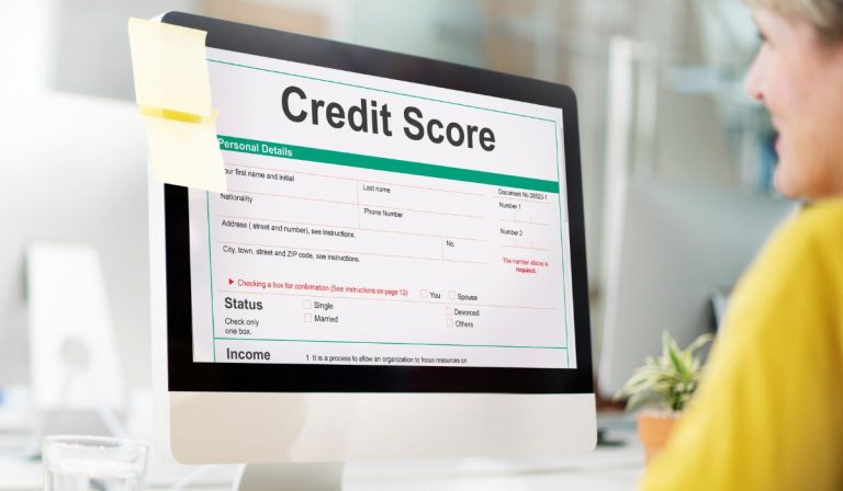 Woman in yellow checking their credit score on a monitor