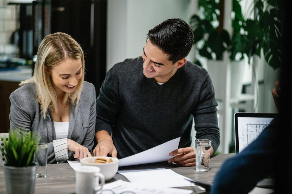 A couple reviews floor plans with a private money lending expert for their new real estate investment project.