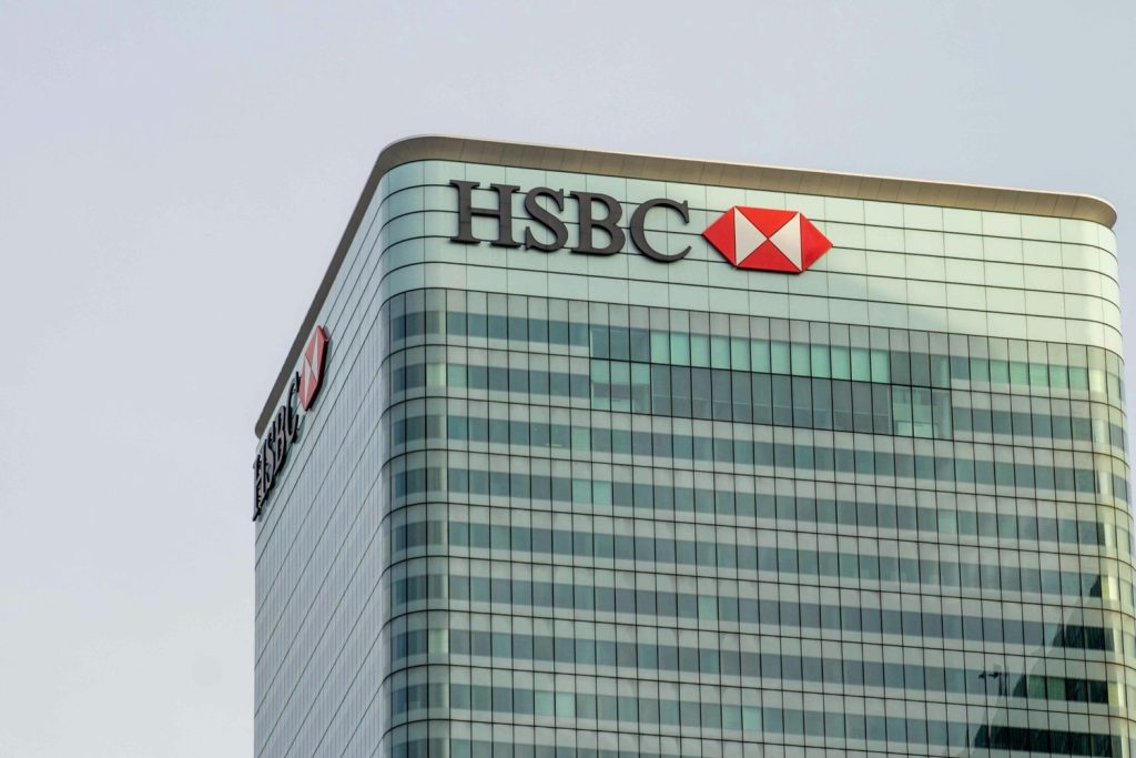 HSBC headquarters building with logo visible on upper floors against clear sky.