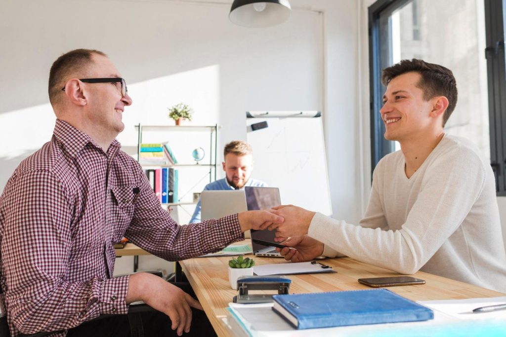 Two business partners shake hands to seal a deal facilitated by private money lending for a commercial property.