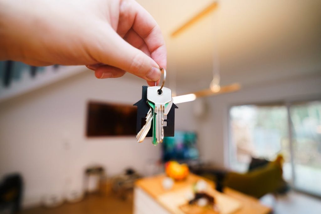 Hand holding a key with a tenants by severalty owned house in the background