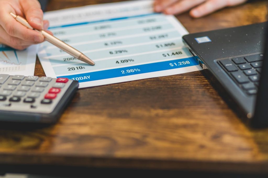 Person holding a pen pointing to interest rates percentages printed on paper