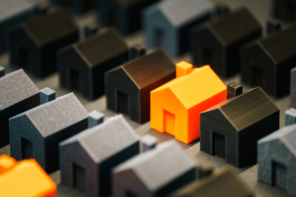 Line of orange and black colored house miniatures illustrating market value of a property