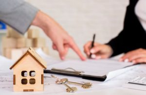Brown wooden cottage with keys on the table with two people signing a lady bird deed