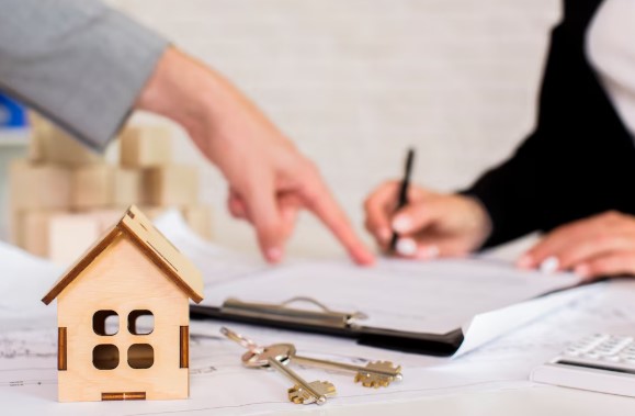 Brown wooden cottage with keys on the table with two people signing a lady bird deed