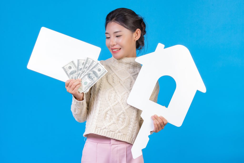 Beautiful woman wearing new long sleeved white carpet that holds house symbol white plaque dollar bill representing rental income under the Augusta Rule