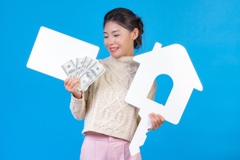 Beautiful woman wearing new long sleeved white carpet that holds house symbol white plaque dollar bill representing rental income under the Augusta Rule