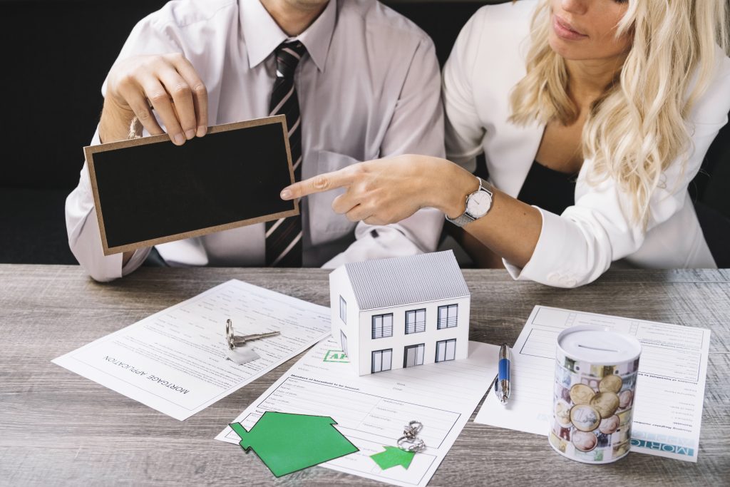 Man and woman with miniature white house and phone reading through the habendum clause of the contracts
