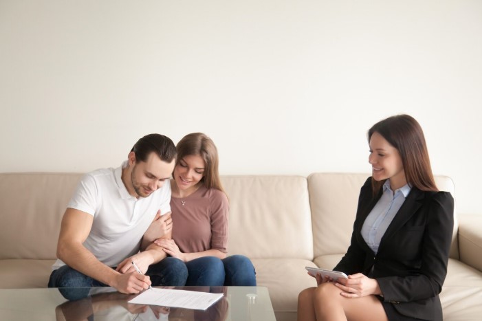 Young man signing lady bird deed papers with his wife