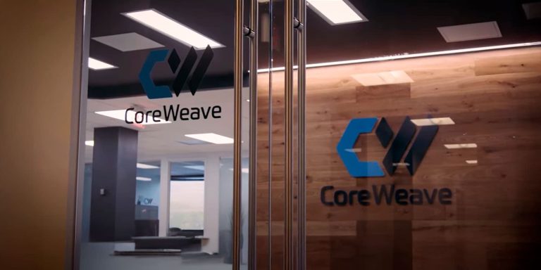 CoreWeave logo displayed on a glass door at the company's office entrance, with a wood-paneled wall and modern interior visible in the background for CoreWeave news
