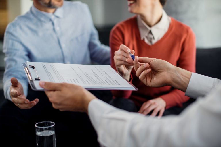 Closeup of unrecognizable couple signing a contract with an insurance company after reviewing the principles of insurance