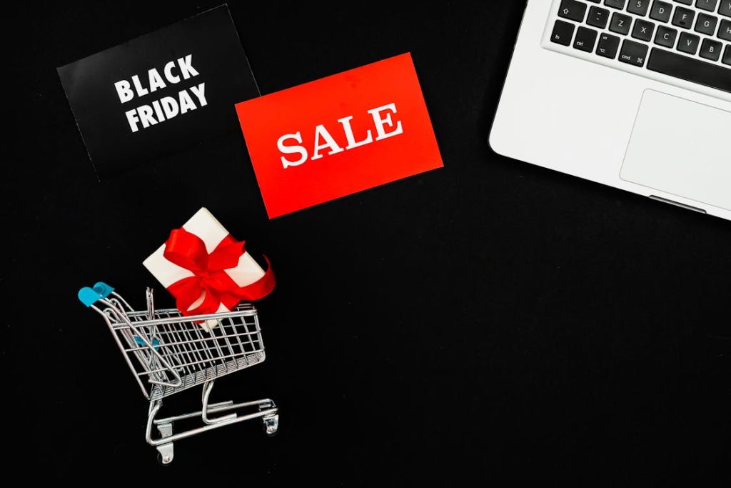Laptop, small cart, sale card, and a Black Friday sale card on a black table for types of pricing