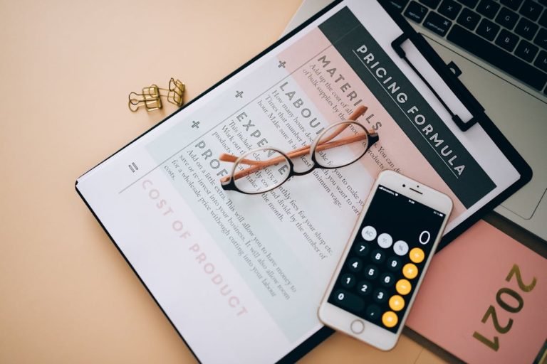 A clipboard with paper containing pricing calculation, glasses, and calculator on a table for types of pricing