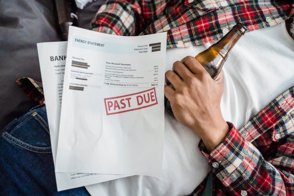 Man living paycheck to paycheck with bill past due on top of his stomach