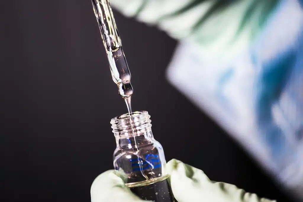 a close view of a laboratory technician in the process of pipetting a sample of vitamin E acetate, Vivo Capital