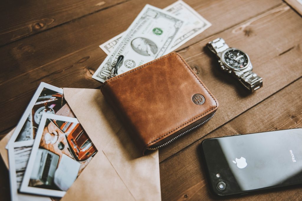 Wallet, money, and watch on a table while calculating fluctuating income