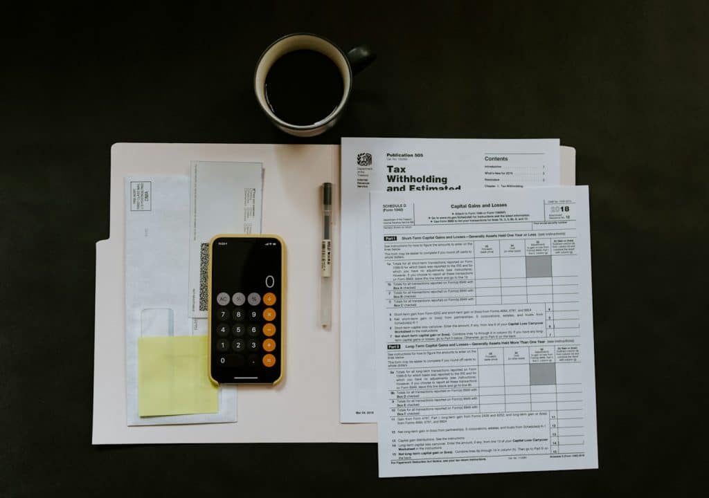 Smartphone with calculator on top of documents to calculate gross income vs. net income