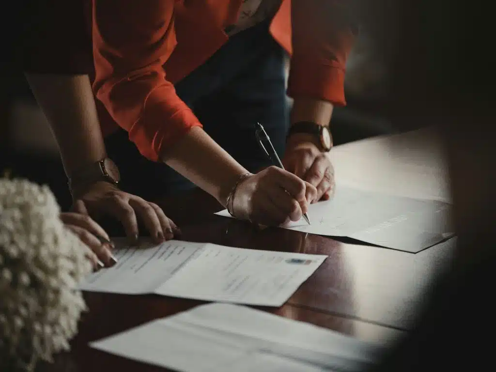Person in orange long sleeve shirt writing on white paper about fiduciary bond