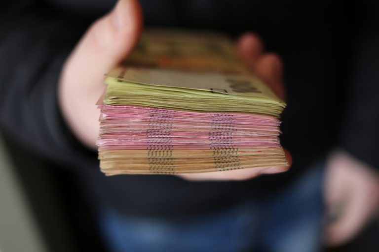 Person holding a stack of paper bills from their fluctuating income