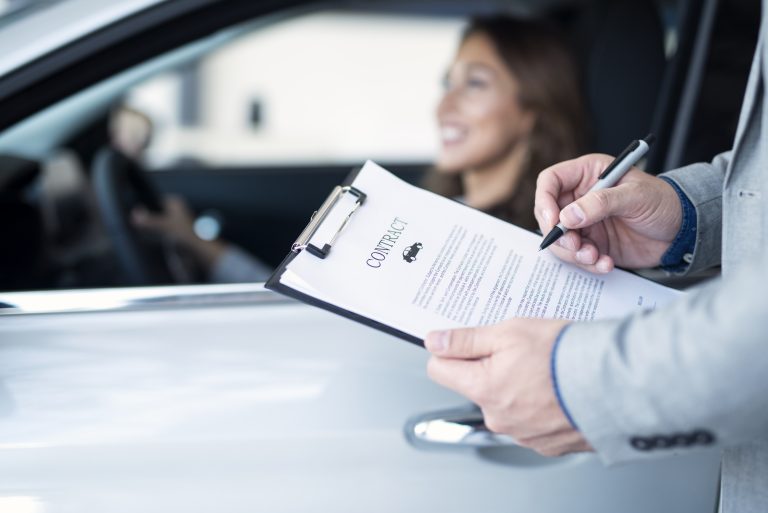 Happy customer buying brand new car with guaranteed asset protection at local car dealership.