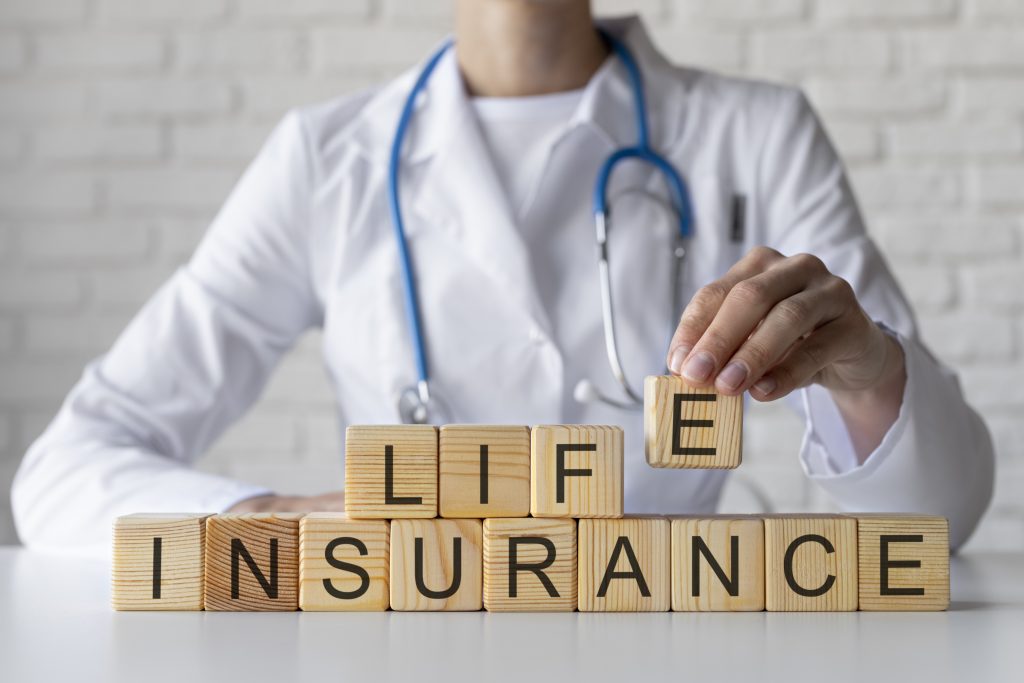 Close up of a doctor holding wooden cubes with letters forming "life insurance"