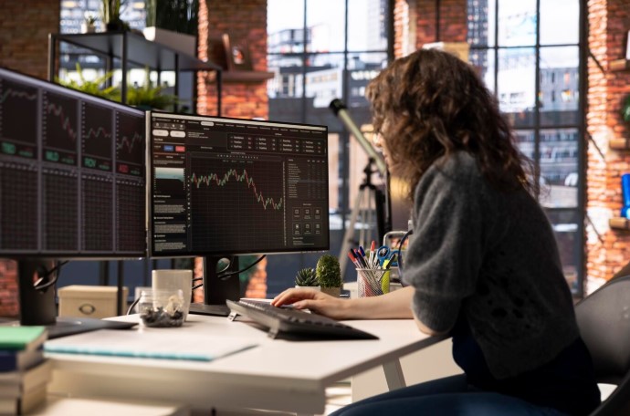 Young woman studies stock trading charts on her computer