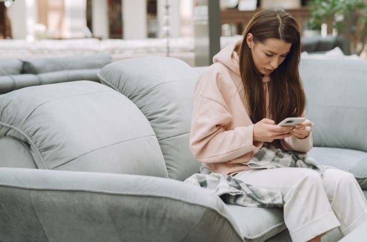 Woman in pink top sitting on couch using phone
