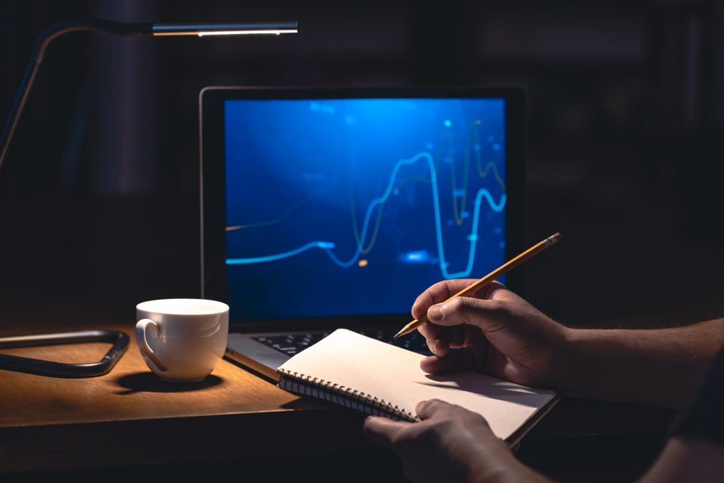 Person calculating their investments using the Treynor ratio while monitoring on a monitor