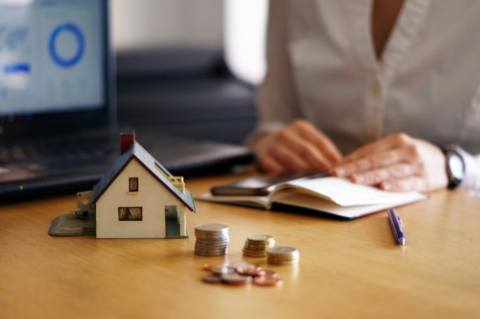 Woman reviewing piggyback loan with house model and coins on her table