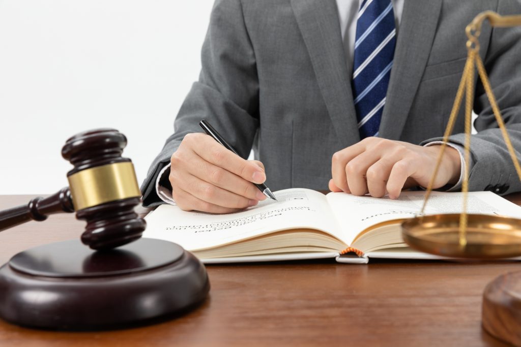 Person writing structured settlement terms with gavel