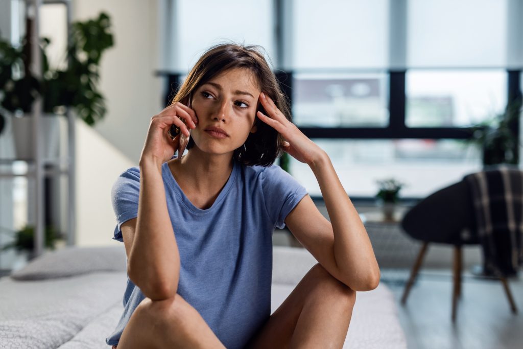Young sad woman communicating over mobile phone and looking away while thinking of short sale vs foreclosure