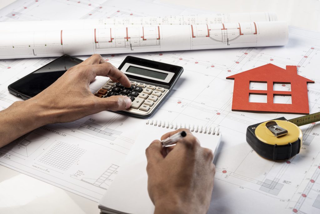 Hands writing on paper while using calculator for a property's assessed value