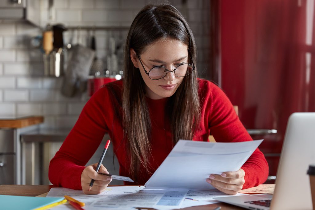 Woman in red with glasses reviewing her financial documents, including rental history report