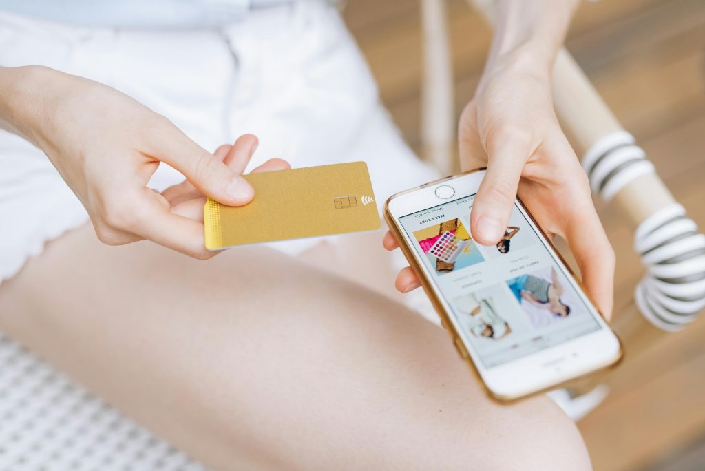 Woman shopping online holding a credit card and smartphone