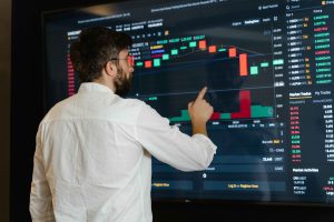 Trader analyzing candlestick charts on a large screen while thinking of bear market strategies