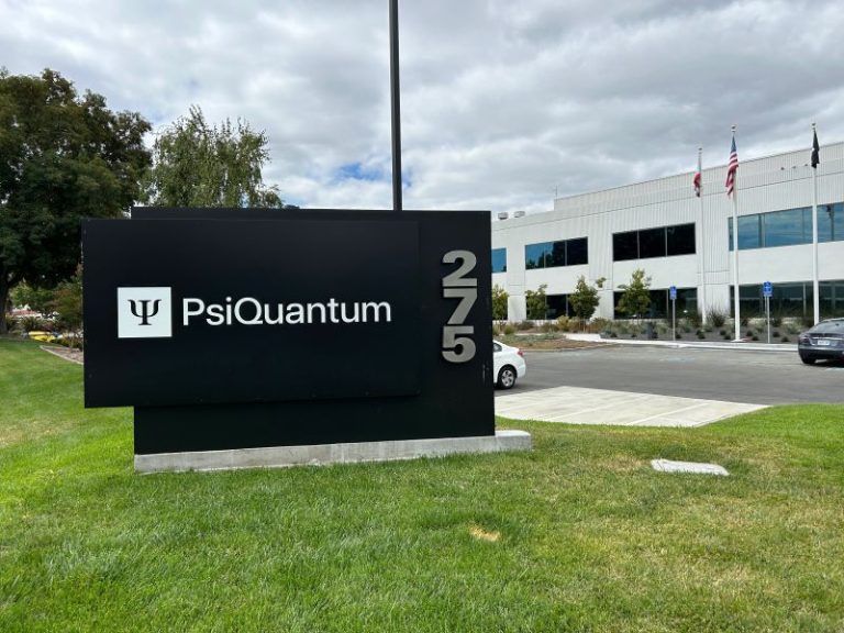 Exterior sign for PsiQuantum Australia, featuring the company logo and name in front of a modern office building with flags and a parking lot.