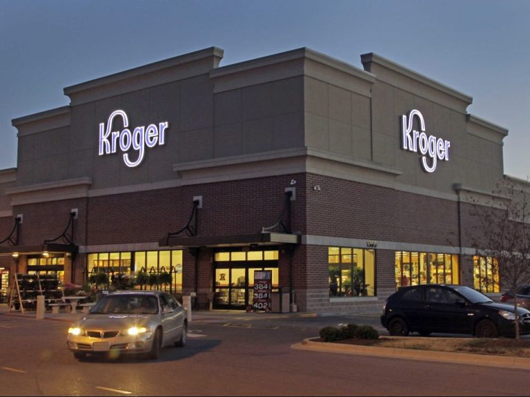 Kroger grocery store exterior at dusk with parking lot and customers arriving.
