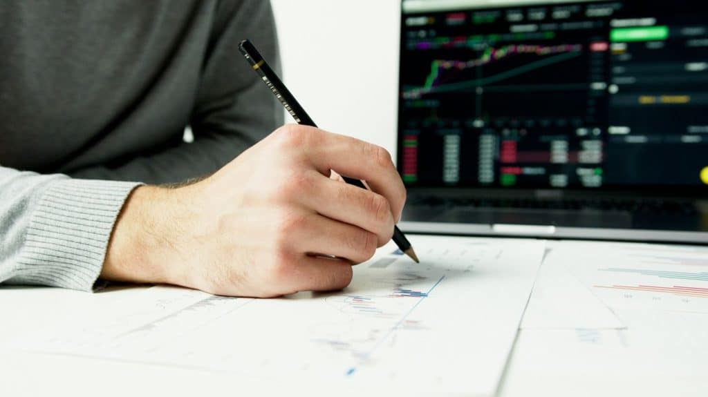 Investor analyzing financial charts and market corrections with stock data displayed on laptop screen.